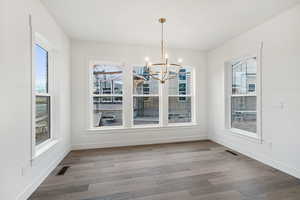 Unfurnished dining area featuring hanging lights, plenty of natural light, and wood finished floors