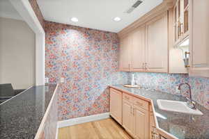 Kitchen with light wood-style flooring, wallpapered walls, recessed lighting, and tile countertops