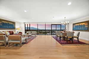 Dining space with expansive windows, light wood-style floors, crown molding, a chandelier, and a mountain view