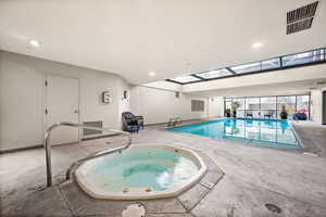 Indoor pool featuring a hot tub, a skylight, and a sunroom