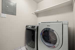 Laundry room with electric panel and washing machine and clothes dryer