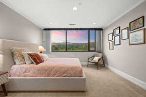 Bedroom with ornamental molding and light carpet