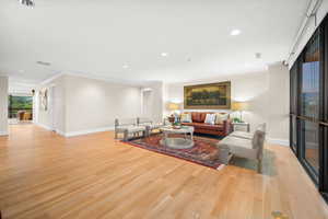 Living room featuring recessed lighting, light wood-style flooring, and ornamental molding