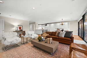 Living area with hanging lights, crown molding, and light wood-style flooring
