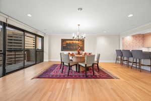 Dining area with light wood-style flooring, hanging lights, and crown molding