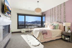 Carpeted bedroom with a mountain view and a glass covered fireplace
