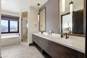 Full bathroom featuring double vanity, a bath, a shower stall, and a mountain view