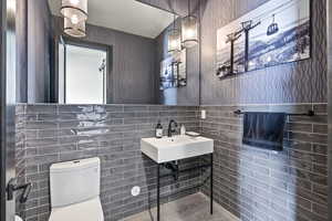 Bathroom featuring wallpapered walls and tile walls