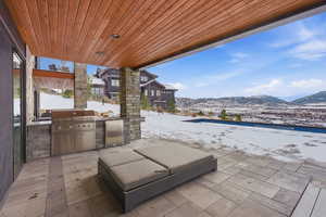 Snow covered patio with exterior kitchen, a mountain view, and a patio