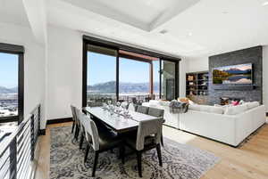 Dining space with a mountain view, light wood finished floors, recessed lighting, a stone fireplace, and built in shelves