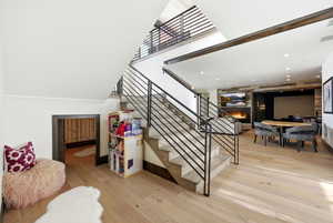 Stairs with wood-type flooring, a warm lit fireplace, and a high ceiling