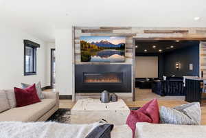 Living area with a glass covered fireplace, wood finished floors, and recessed lighting