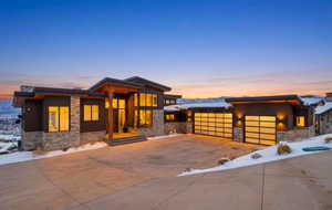 View of front of property with stone siding, concrete driveway, and a garage