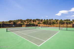 View of tennis court featuring view of scattered trees