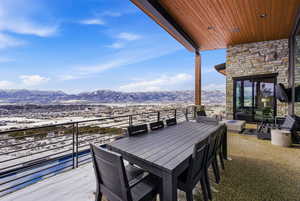 Snow covered deck with a patio area, outdoor dining area, and a mountain view