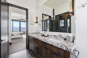 Full bath featuring connected bathroom, double vanity, light carpet, and a mountain view