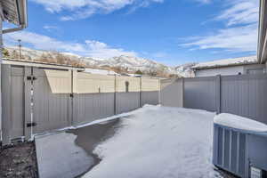 Snowy yard with a mountain view and a gate