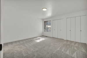Unfurnished bedroom featuring light carpet and two closets