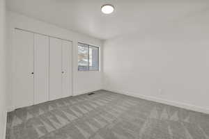 Unfurnished bedroom featuring light carpet and a closet
