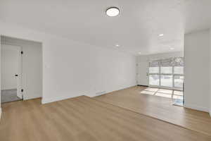 Empty room with light wood finished floors and recessed lighting