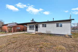 Ranch-style house featuring an attached carport, brick siding, driveway, and a chimney