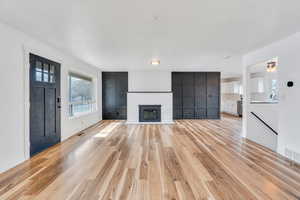 Unfurnished living room with light wood-style flooring and a brick fireplace