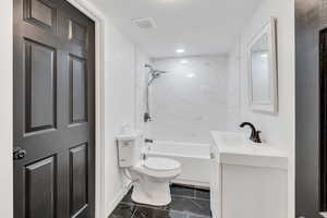 Full bathroom with washtub / shower combination, vanity, dark marble finish flooring, and a textured ceiling