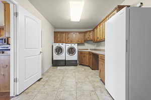 Laundry room featuring separate washer and dryer, cabinet space, and a textured ceiling