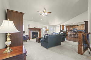 Living area with light carpet, a fireplace, a ceiling fan, lofted ceiling, and suspended lighting