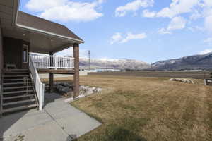 View of green lawn with a mountain view, a view of rural / pastoral area, and a patio area