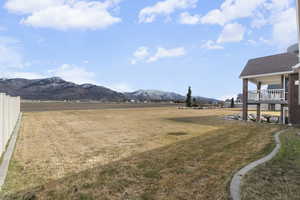 View of green lawn featuring a mountain view and a rural view