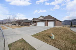 View of front of home with a mountain view, a garage, concrete driveway, and brick siding