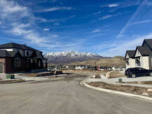 View of asphalt road featuring curbs, sidewalks, a mountain view, and a residential view