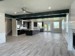 Kitchen featuring open floor plan, beam ceiling, a center island, ceiling fan, and decorative backsplash