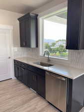 Kitchen featuring dishwasher, light stone counters, and light wood finished floors