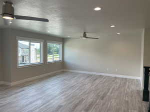 Empty room featuring light wood-type flooring, recessed lighting, a ceiling fan, and a textured ceiling