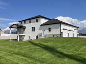 Rear view of house with a patio, a garage, stucco siding, a shingled roof, and a mountain view