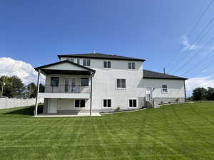 Rear view of property featuring a patio, a yard, and stucco siding