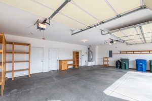 Garage with water heater, electric panel, and a garage door opener