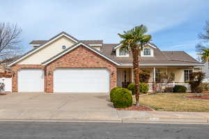 View of front of house featuring covered porch, a garage, driveway, and a front lawn