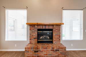 Detailed view of carpet flooring and a brick fireplace