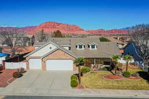 View of front facade with a garage, a tile roof, driveway, brick siding, and a mountain view