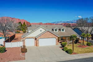 Traditional home featuring an attached garage, brick siding, a mountain view, driveway, and a gate