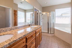 Bathroom with a bath, a stall shower, double vanity, and light tile patterned floors