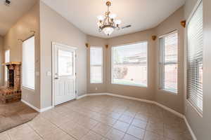 Unfurnished dining area featuring light tile patterned floors, hanging lights, a brick fireplace, and plenty of natural light