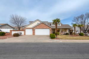Traditional-style home featuring an attached garage, driveway, brick siding, and a tiled roof