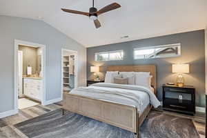 Bedroom featuring a spacious closet, wood finished floors, ceiling fan, and ensuite bathroom