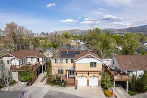 View of front of home featuring solar panels, stucco siding, a mountain view, driveway, and a garage