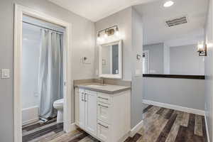 Bathroom with vanity, dark wood-type flooring, and shower / tub combo