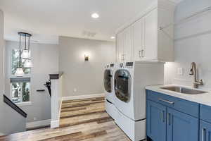 Laundry area featuring independent washer and dryer, recessed lighting, light wood-style flooring, and cabinet space